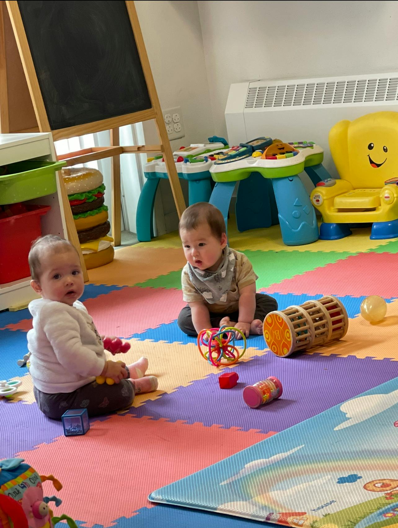 Two children playing with toys on a colorful mat
