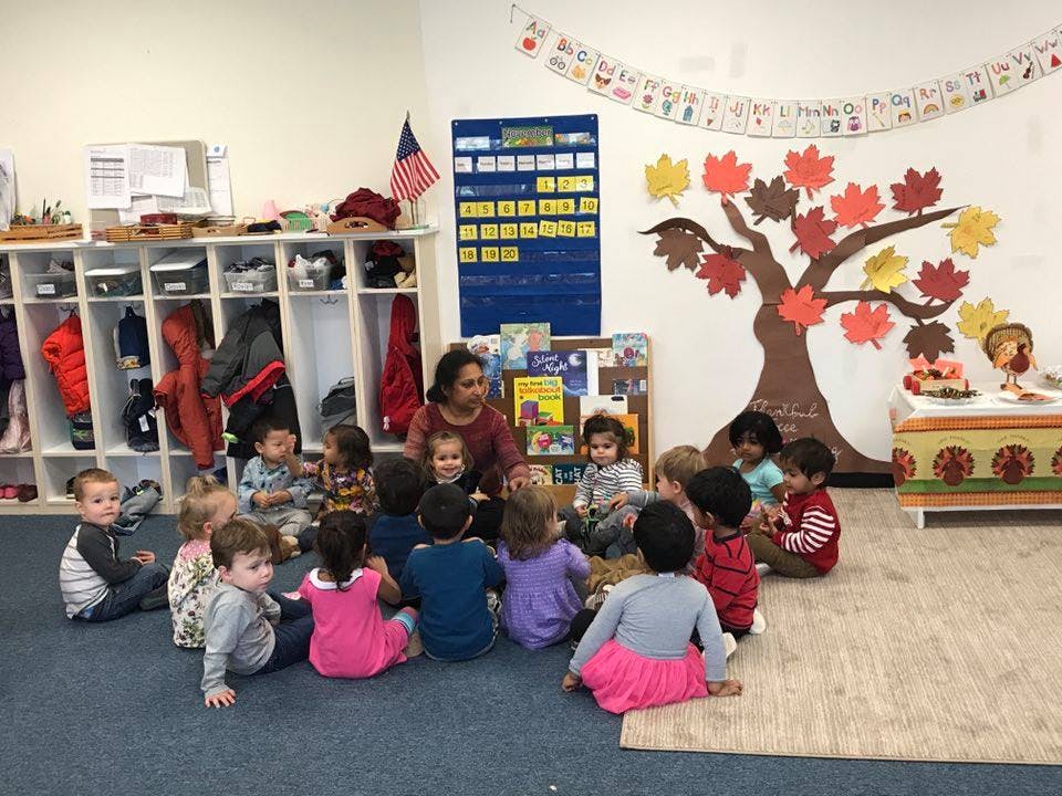 Adult and children sitting on the floor in a classroom