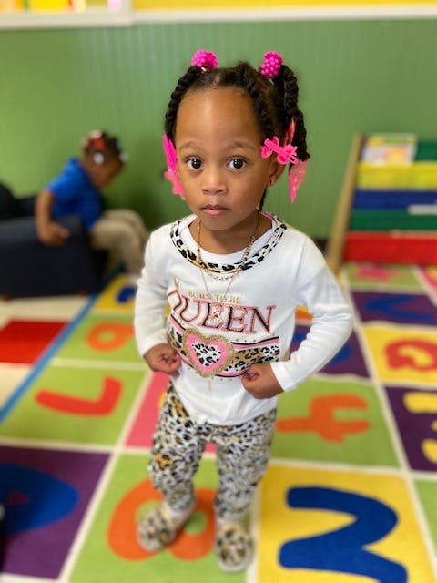 Child standing on a colorful alphabet rug in a classroom