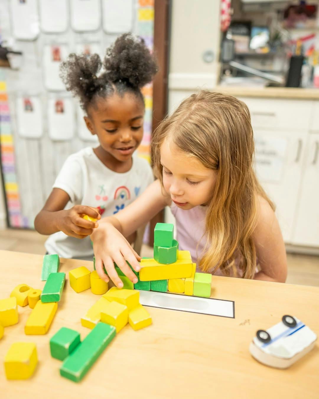 Two children stacking wooden blocks on a table
