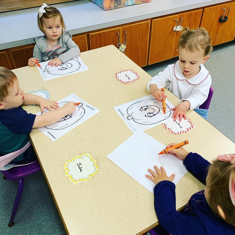 Four children coloring at a table