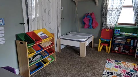 Child's room with toy storage, small table, and colorful rug