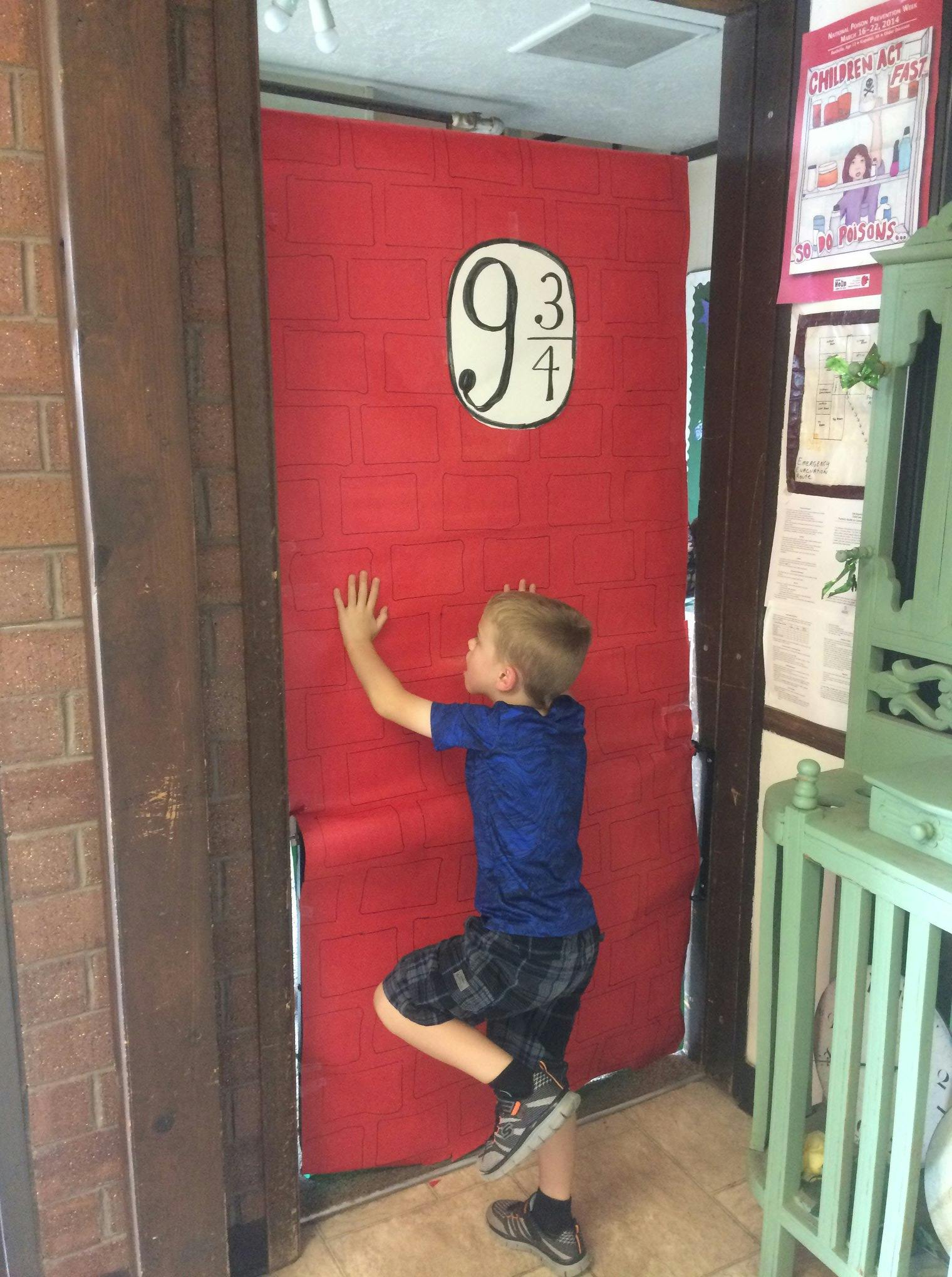 Child pushing against a red door with "9 3/4" on it