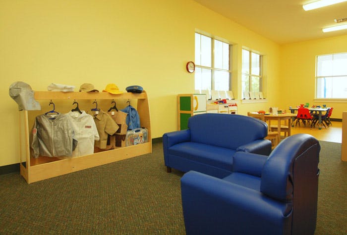 Children's classroom with dress-up clothes, blue couches, and small tables