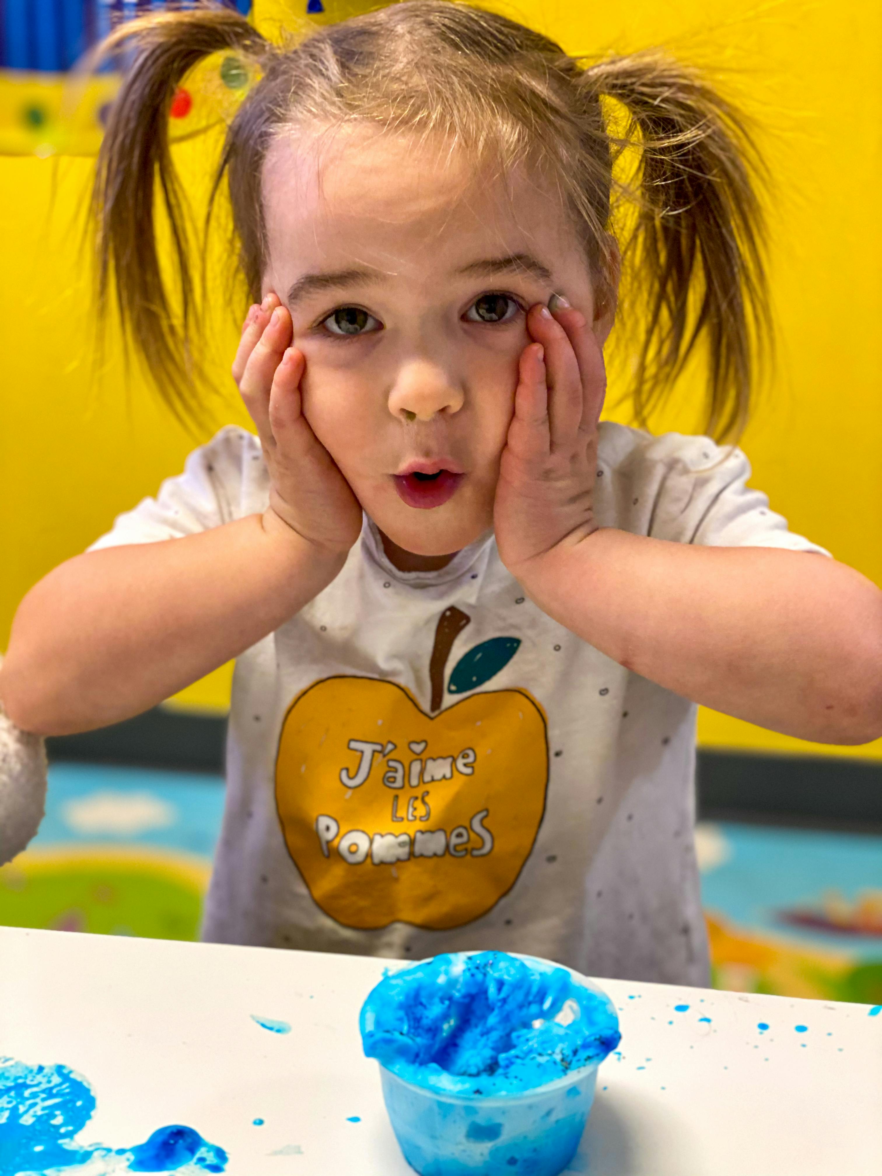 Child with hands on face looking at blue slime