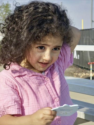 Child with curly hair holding a small object