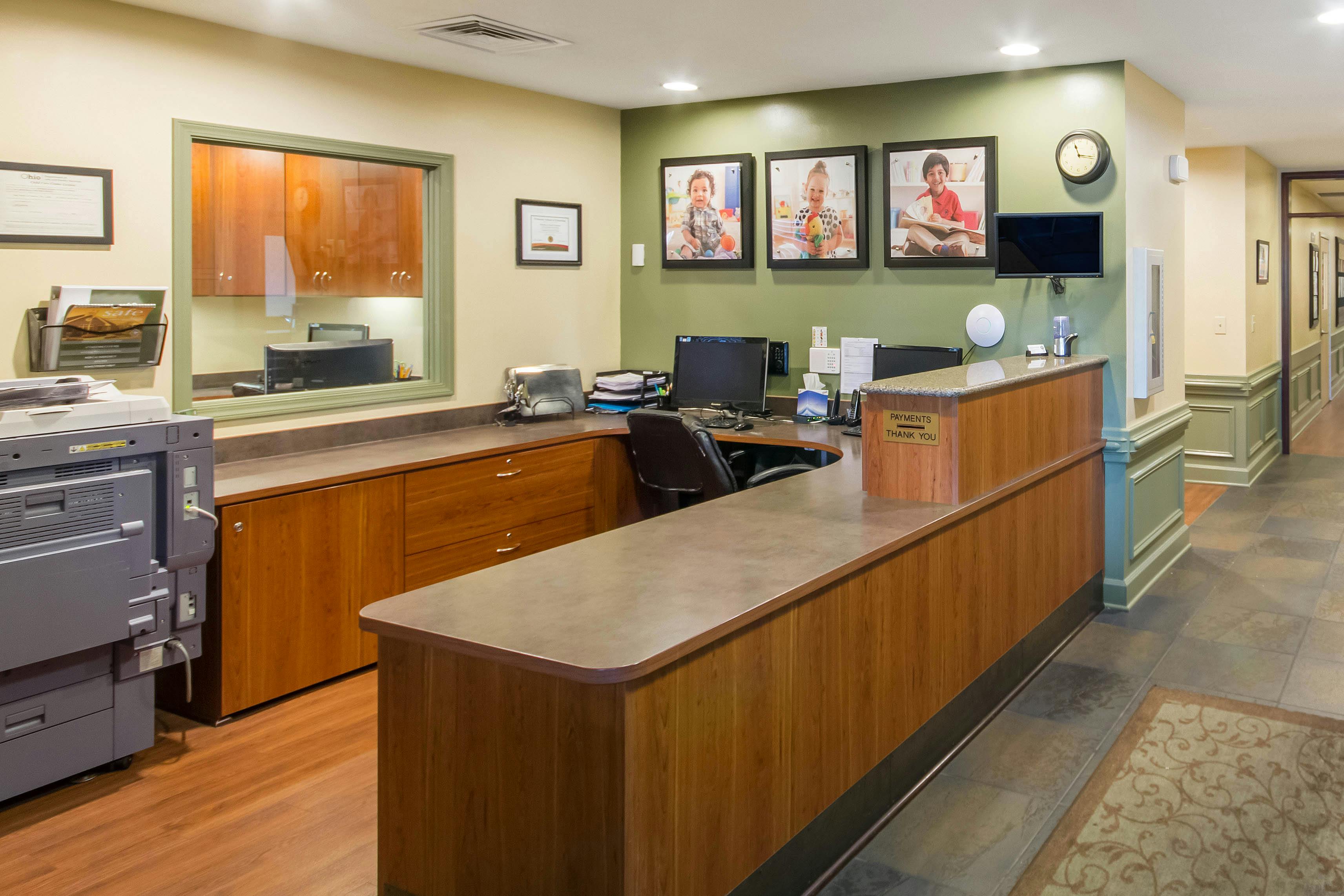 Reception desk with three framed photos of children on the wall