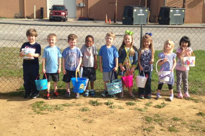 Group of children standing in a line holding buckets and baskets