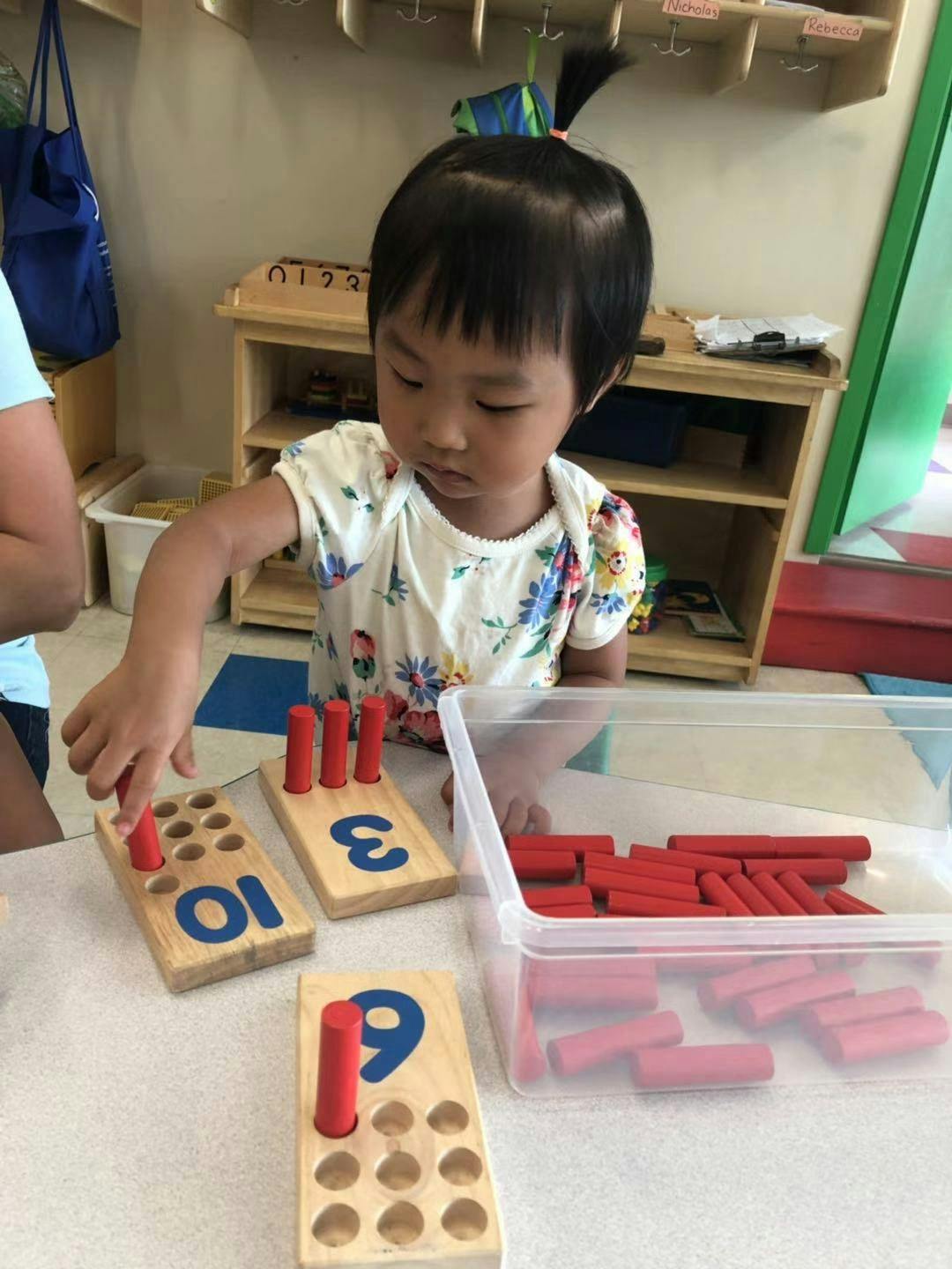 Child playing with wooden number blocks and red pegs