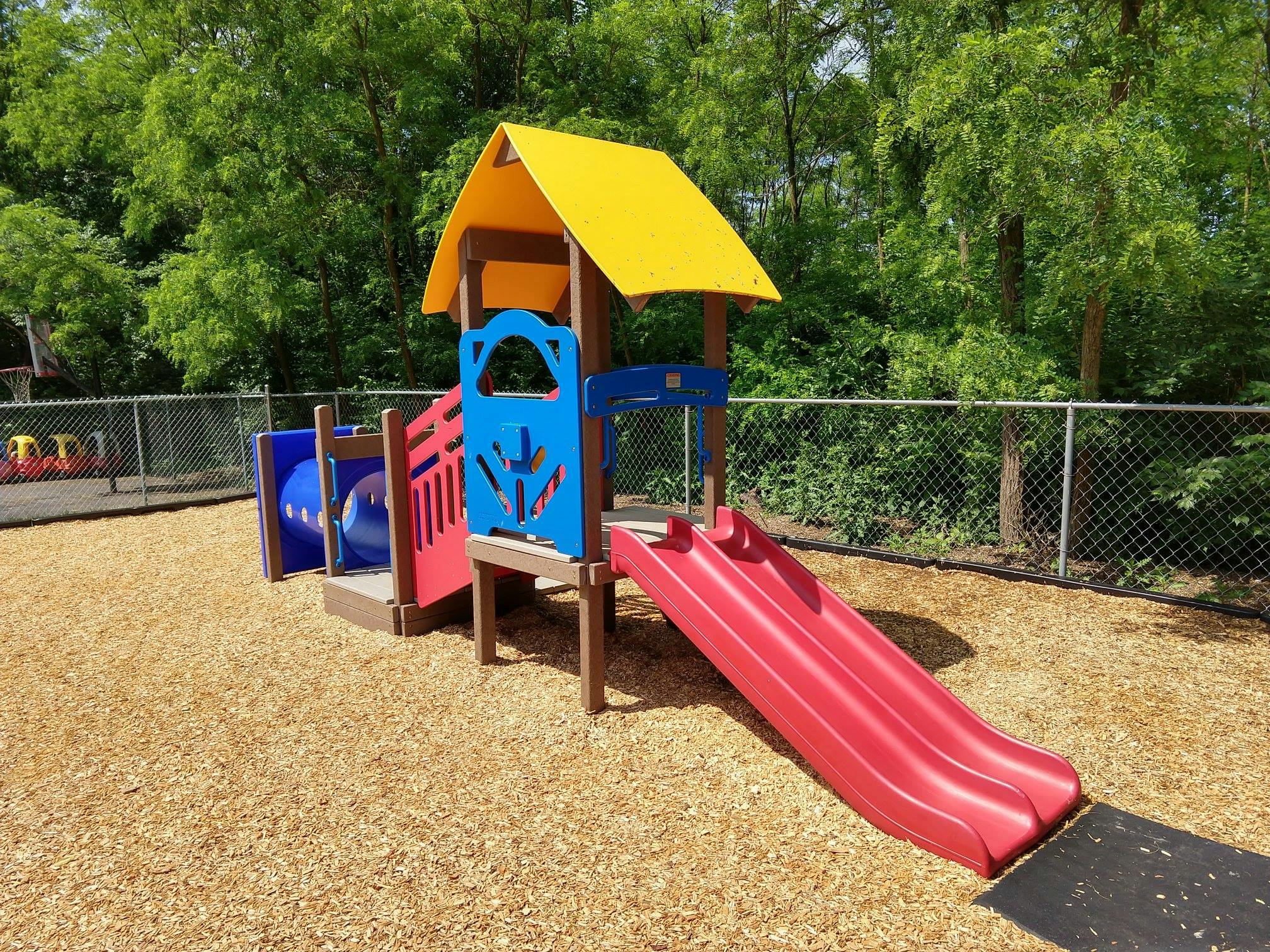 Playground structure with red slide and yellow roof
