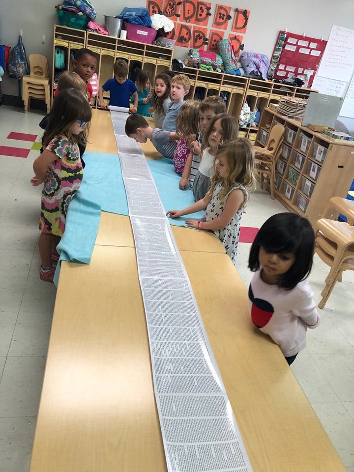 Children gathered around a long table in a classroom