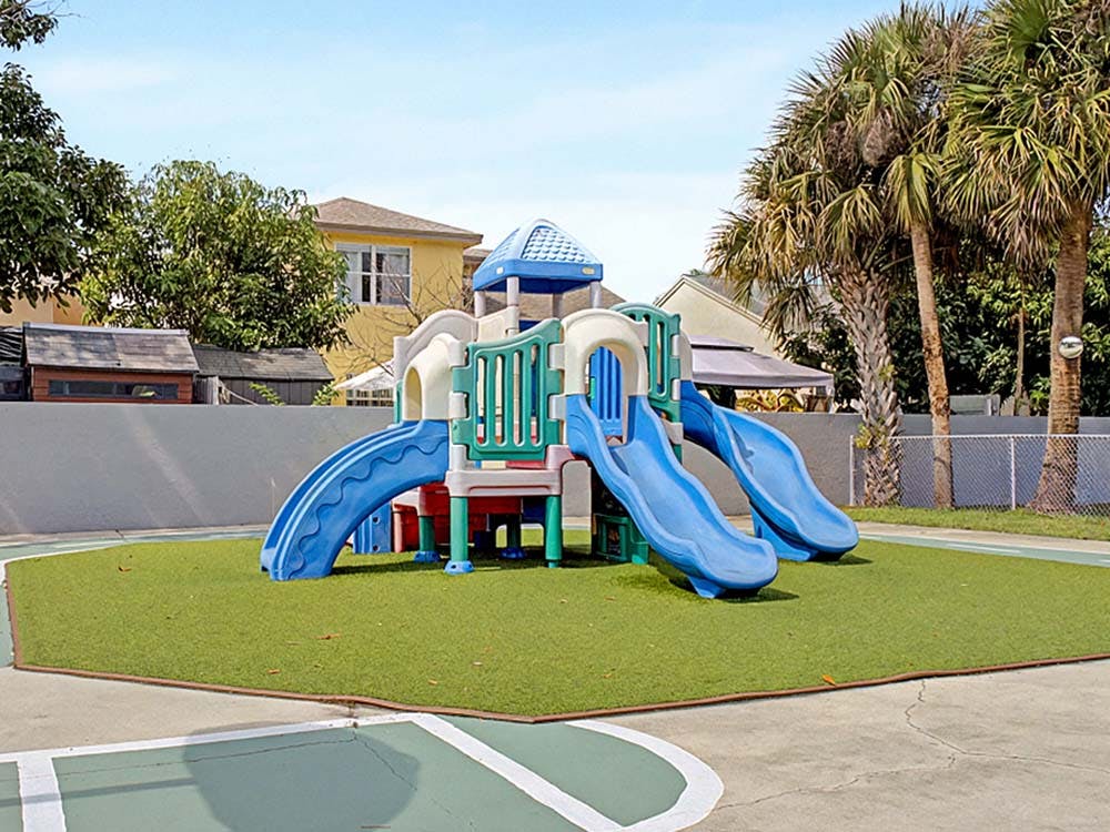 A colorful playground set with multiple slides on artificial grass
