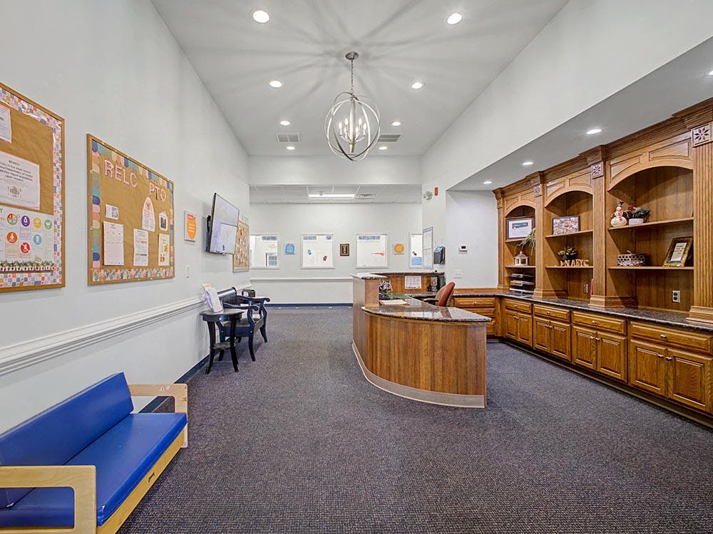 Reception desk in a large lobby with blue couches and bulletin boards