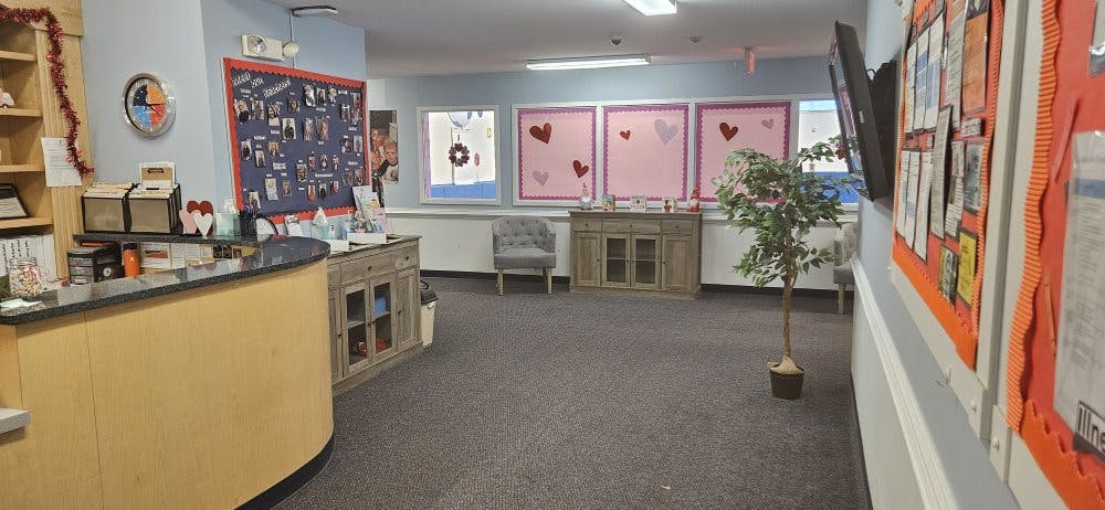 Reception desk with files, a bulletin board, and a decorative tree in a room