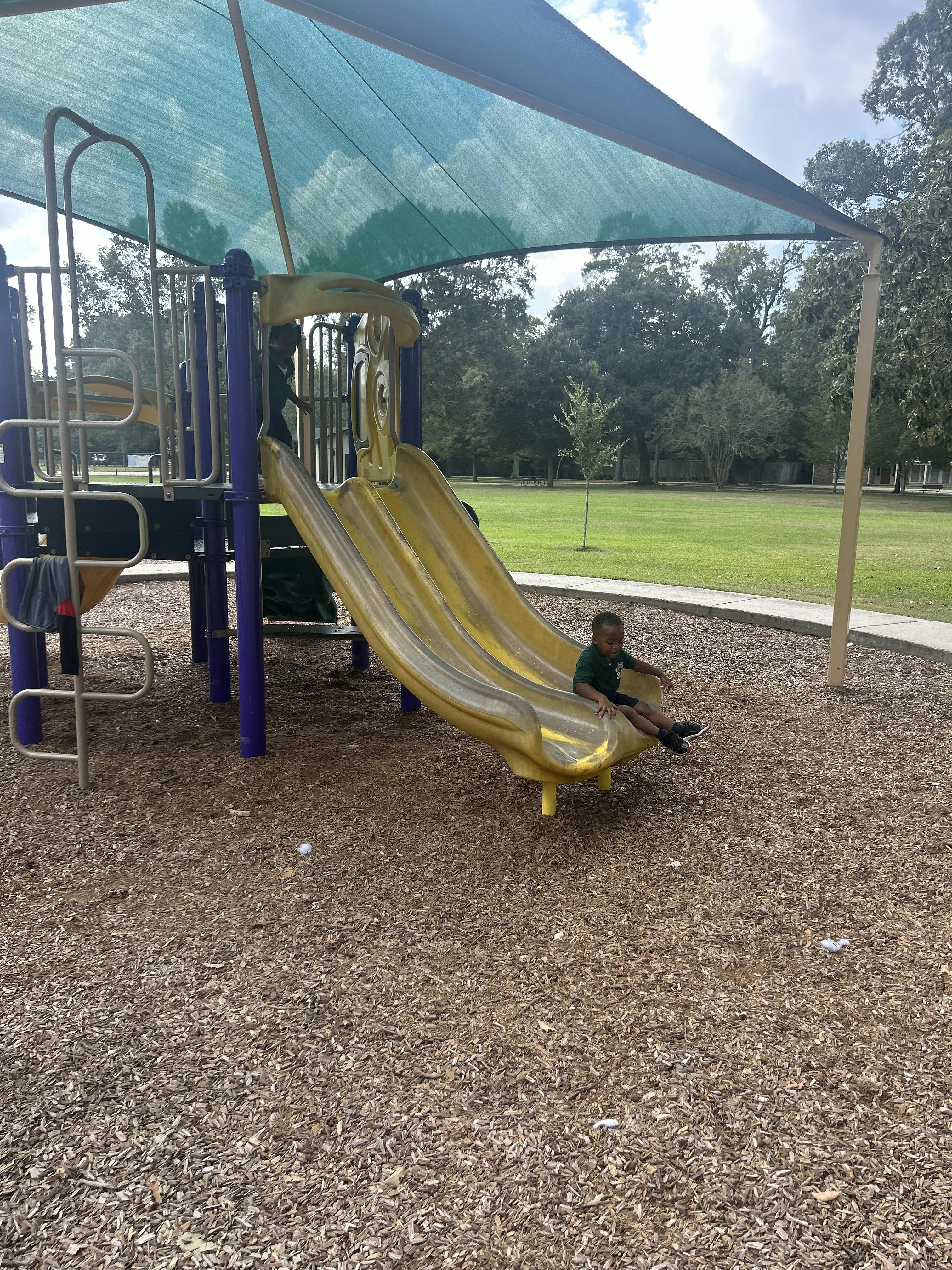 Child on a yellow slide at a playground