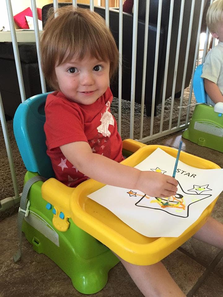 Child in a high chair painting a star
