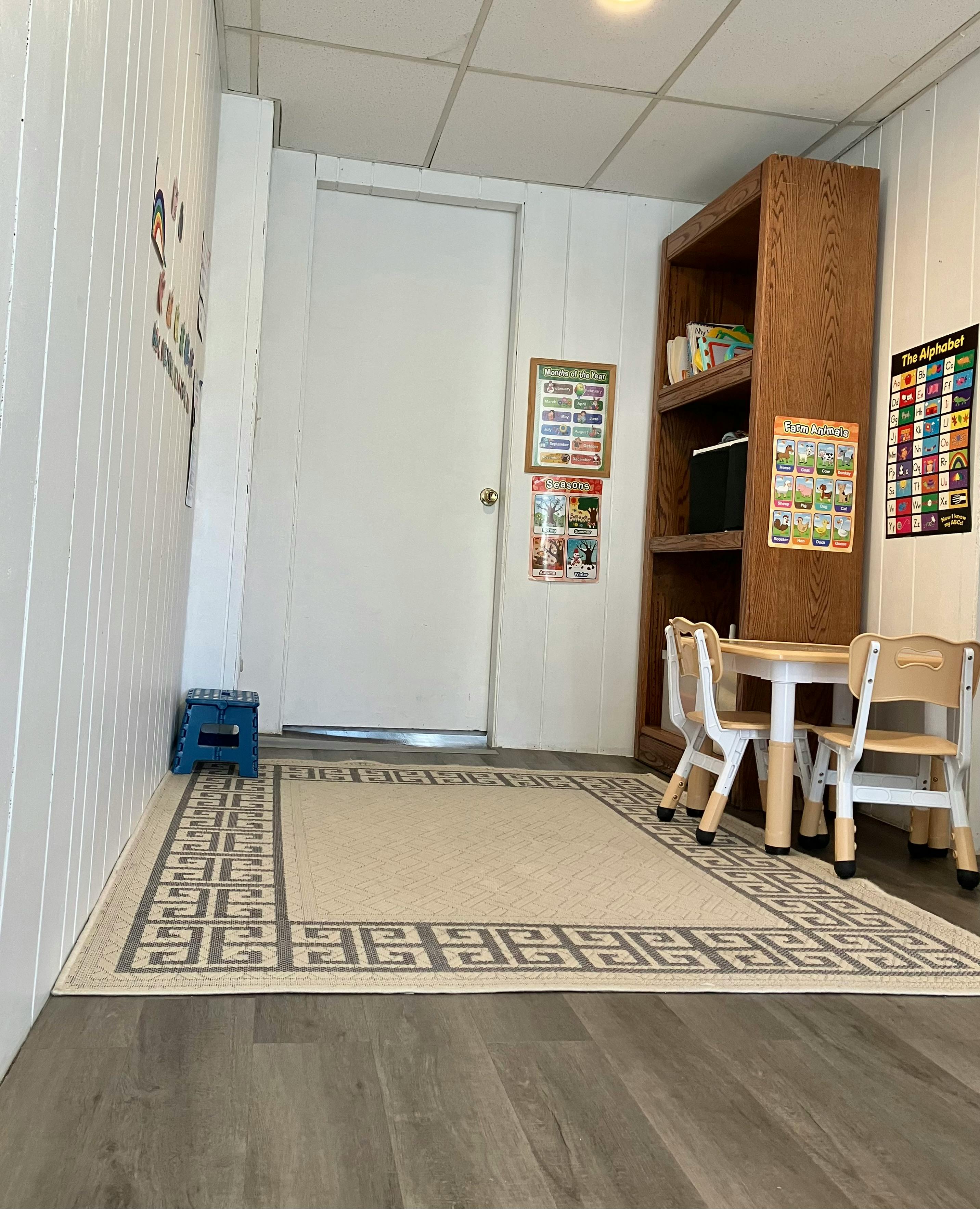 Classroom with a small table and chairs, a bookcase, and educational posters