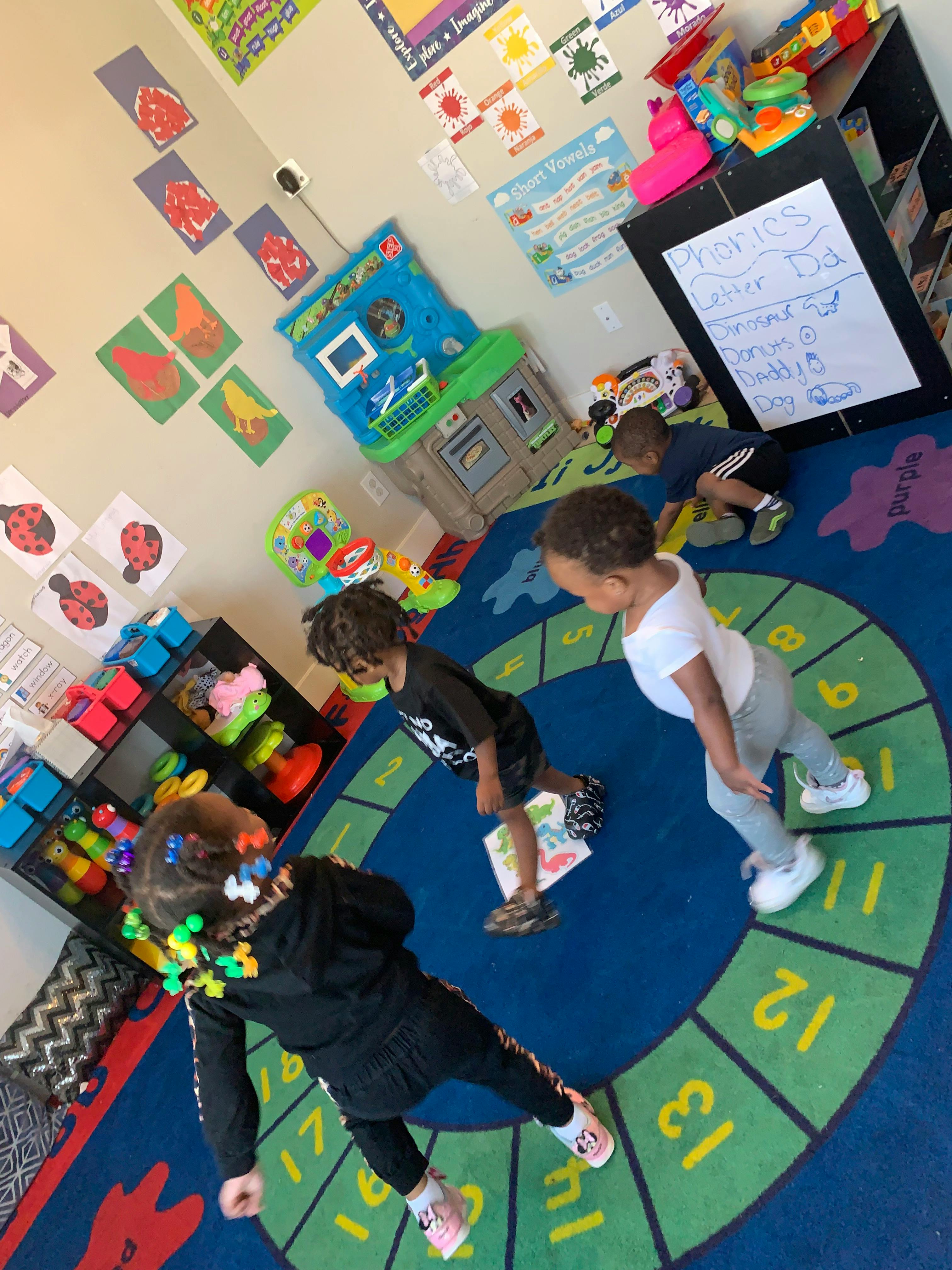 Three children playing on a numbered rug in a classroom
