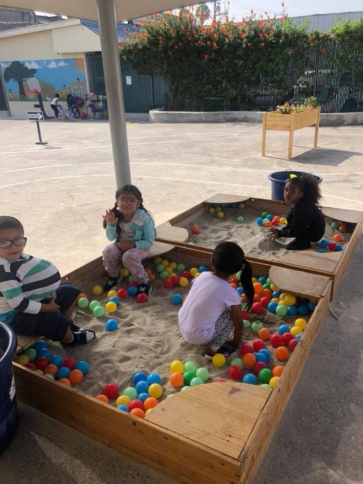 Children playing in a sandbox with colorful balls