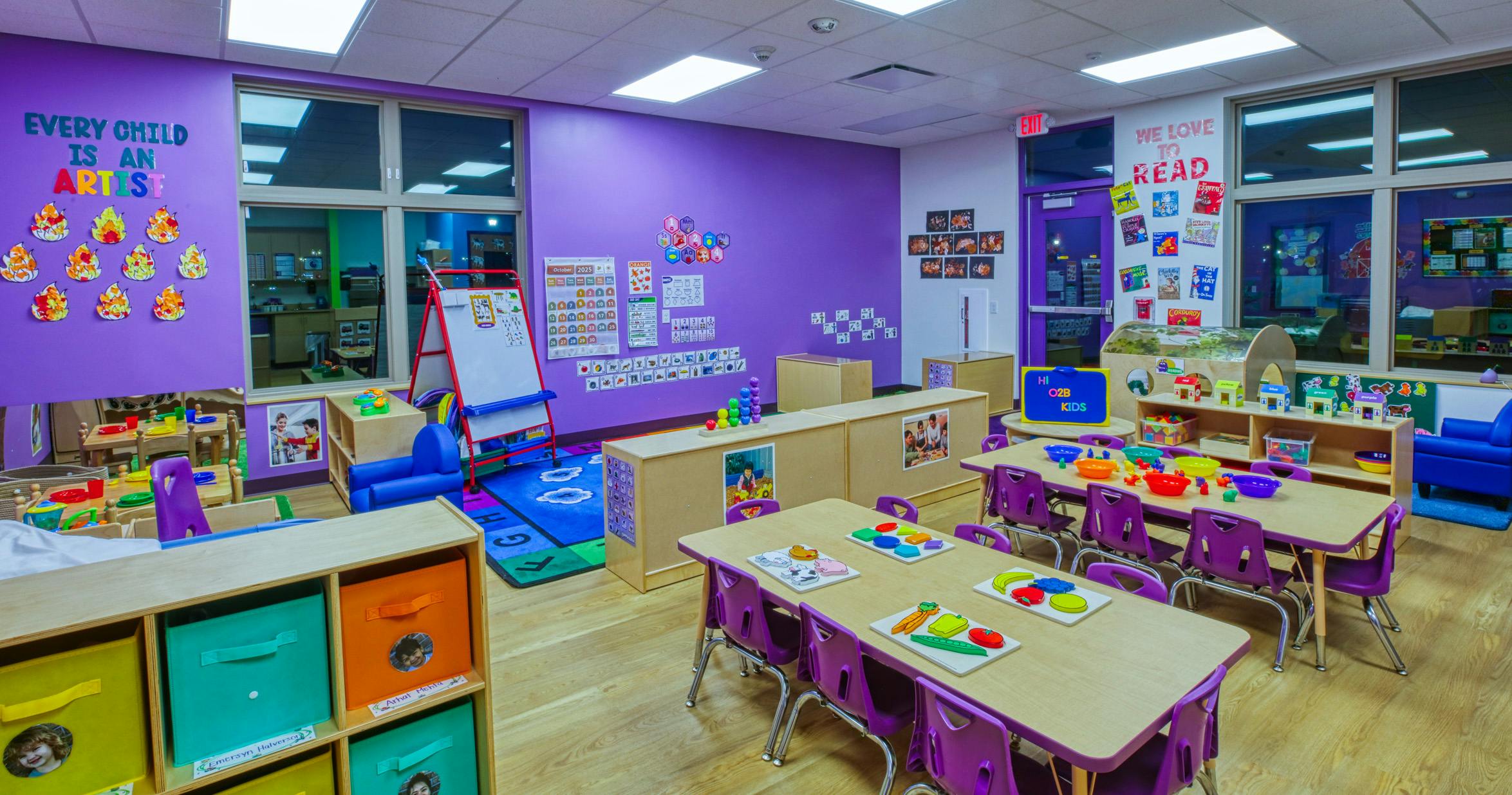 An empty, vibrant purple classroom with tables, chairs, and learning decorations