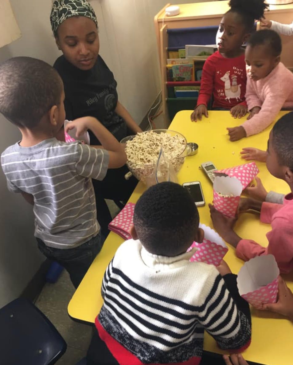 People and children gathered around a table with a bowl of popcorn