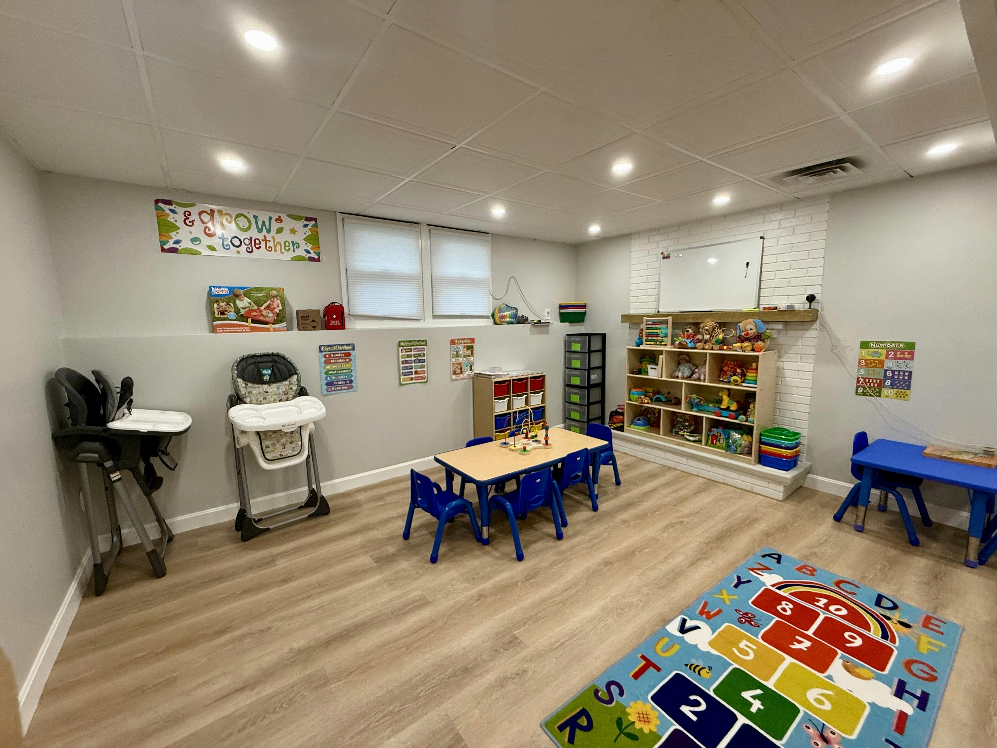 Playroom with small tables and chairs, high chairs, and shelves of toys