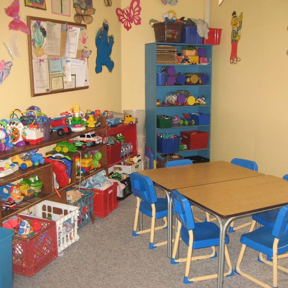 Classroom with tables, chairs, and shelves filled with toys