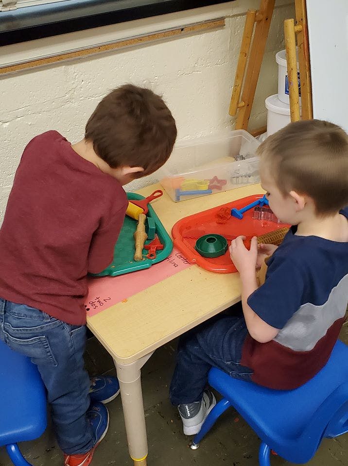 Two children playing with toys at a small table