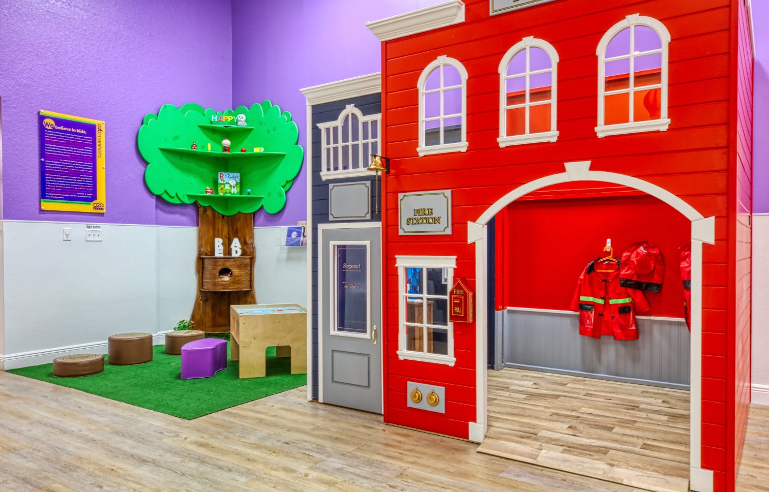 Play area with a red fire station, a blue building, and a tree bookshelf