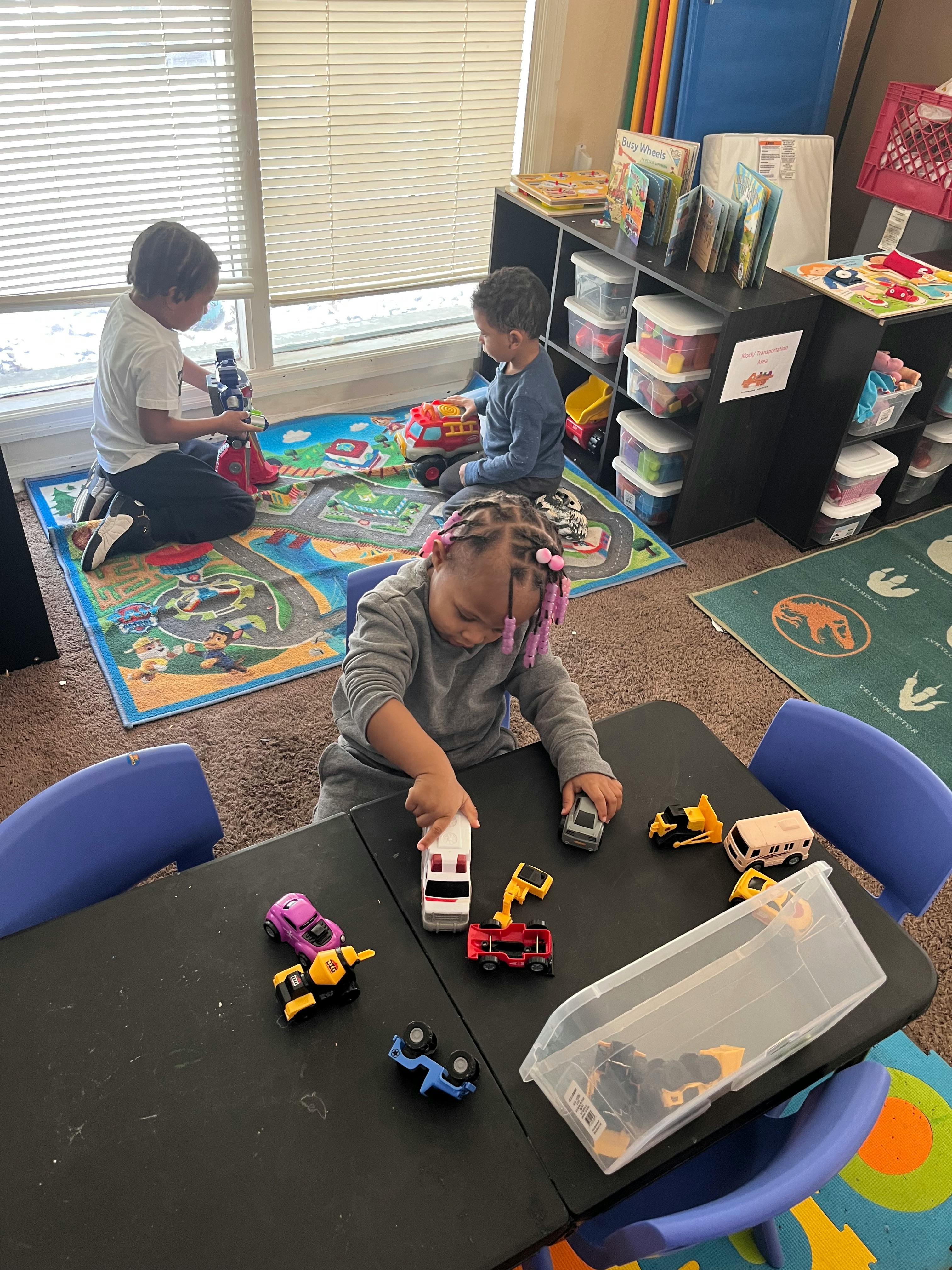 Three children playing with toys in a classroom