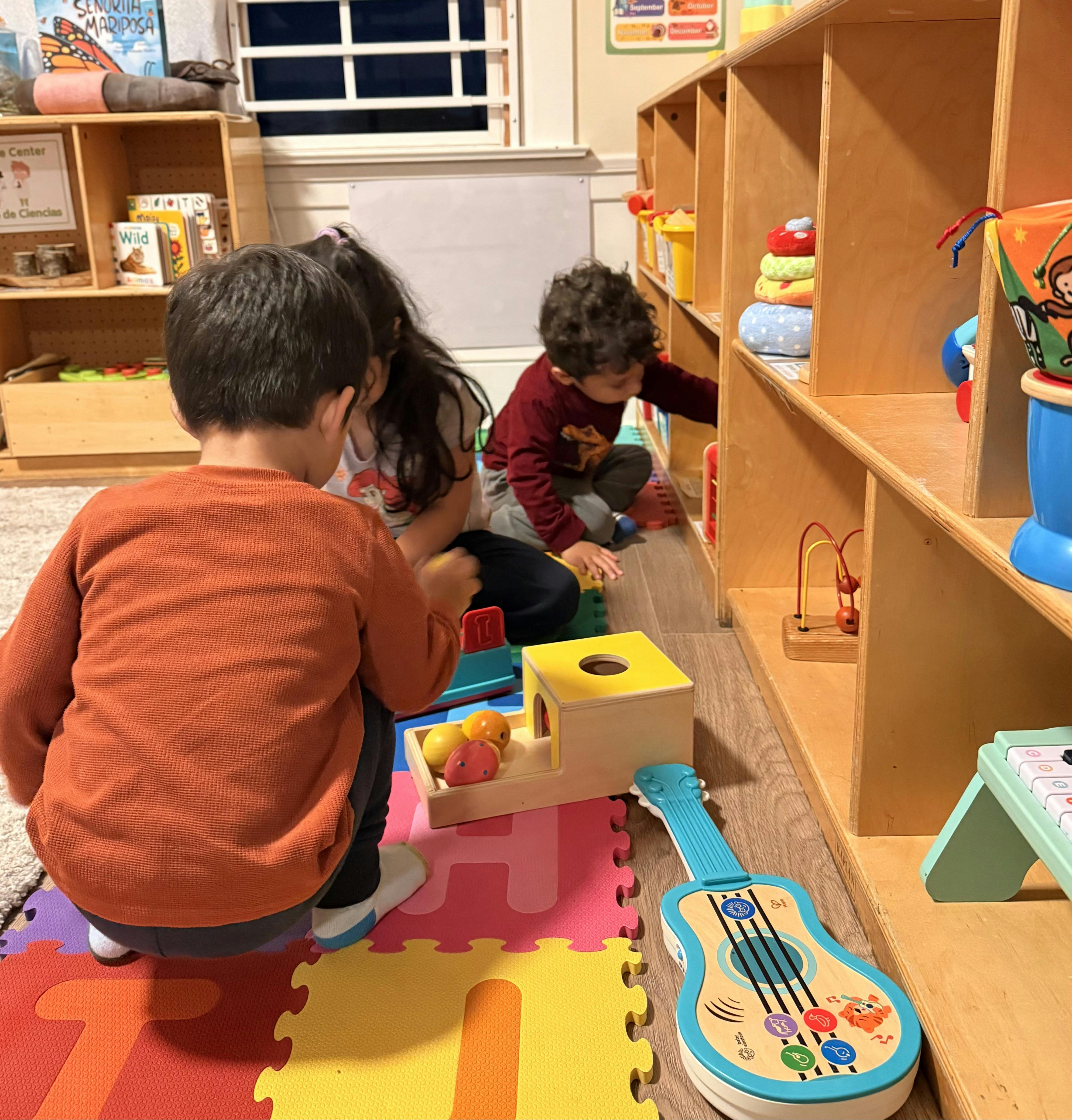 Three children playing with toys on a mat in a room
