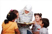 Person in head covering reading a book to children