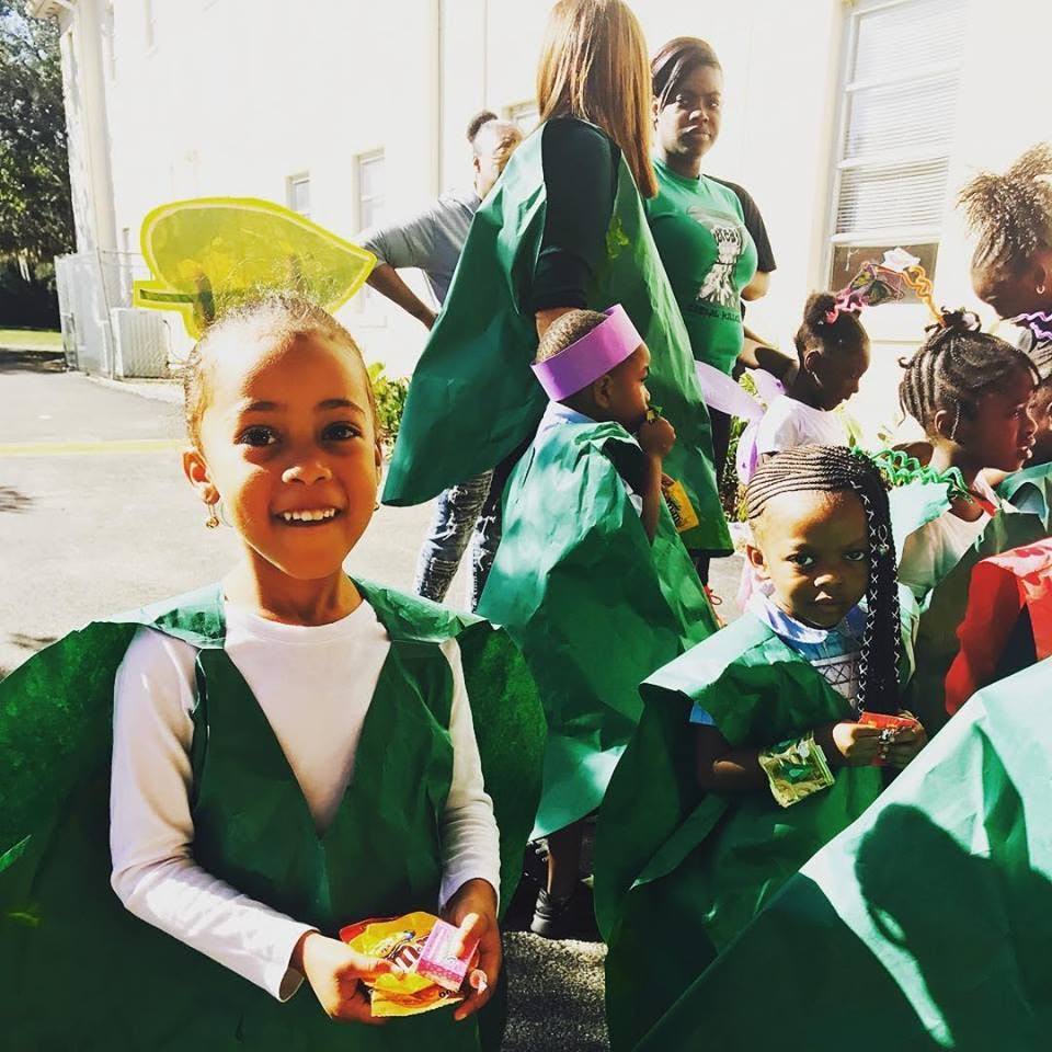 Child in green costume holding candy with other children