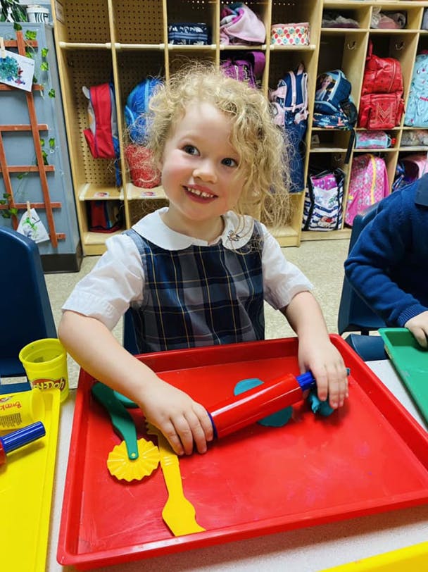 Child playing with play-doh and toys in a classroom