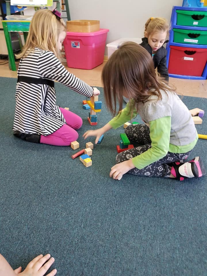 Children playing with blocks on the floor in a classroom