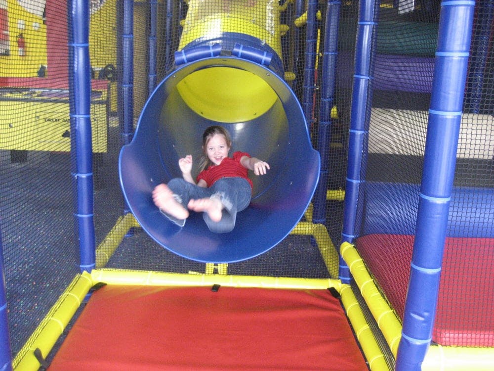 Child sliding down a blue and yellow tube slide
