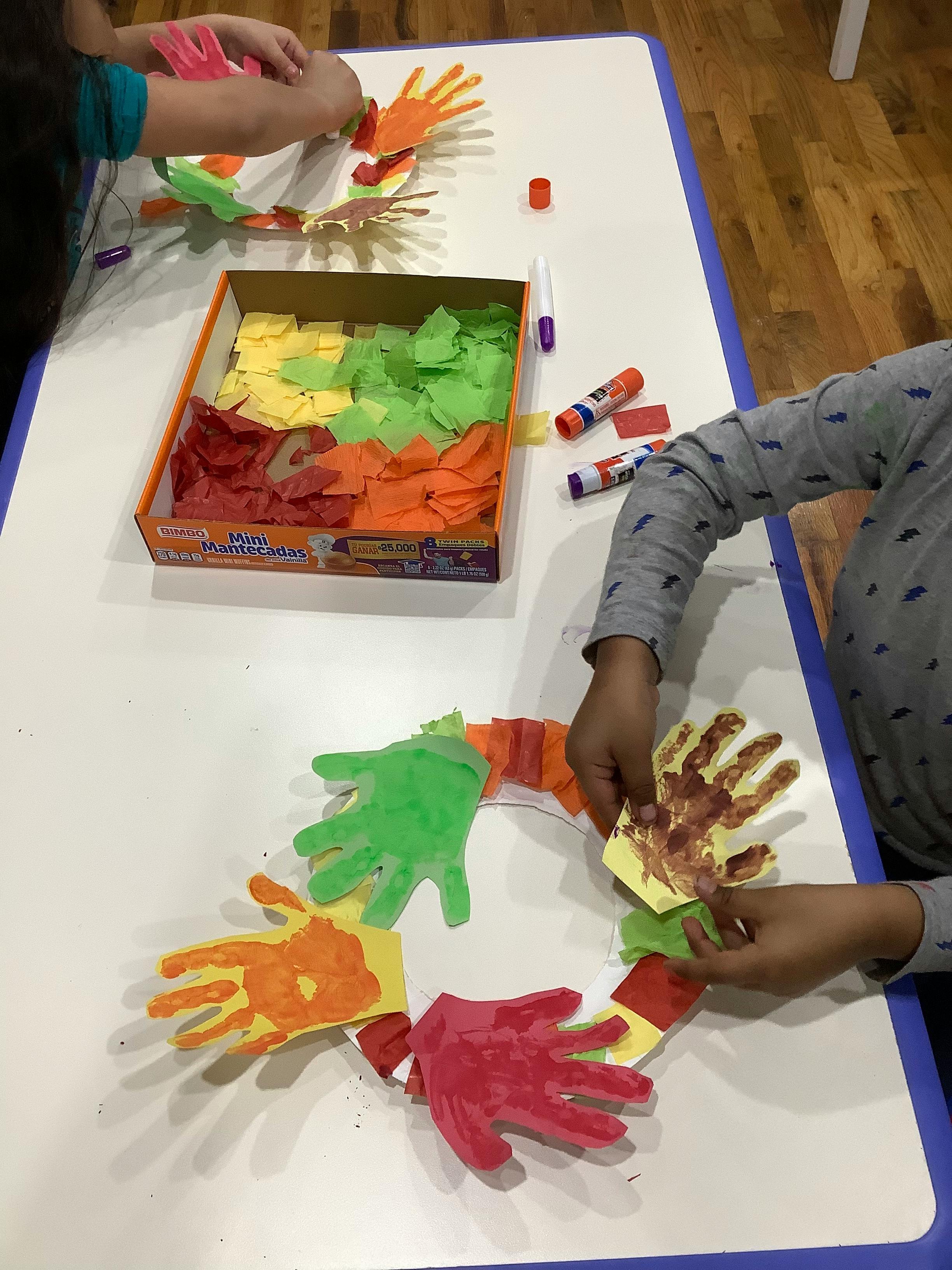 People making crafts with paper hand cutouts and tissue paper