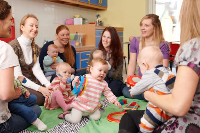 People with babies and children sitting on a mat