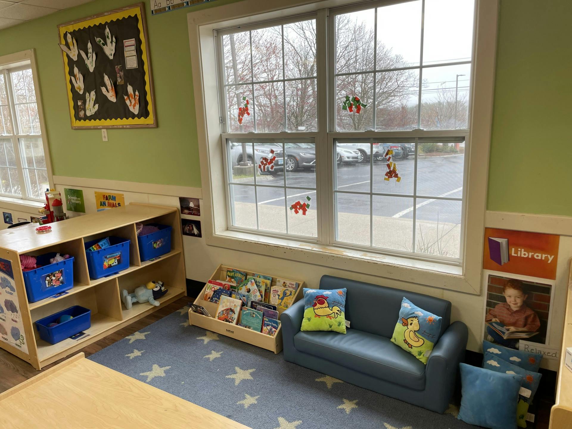 Classroom reading corner with a small sofa, bookshelves, and window art