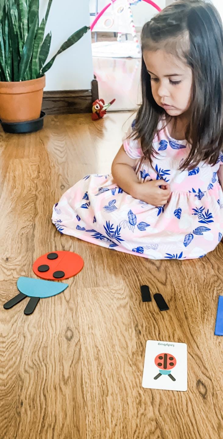Child sitting on floor with ladybug craft pieces and card