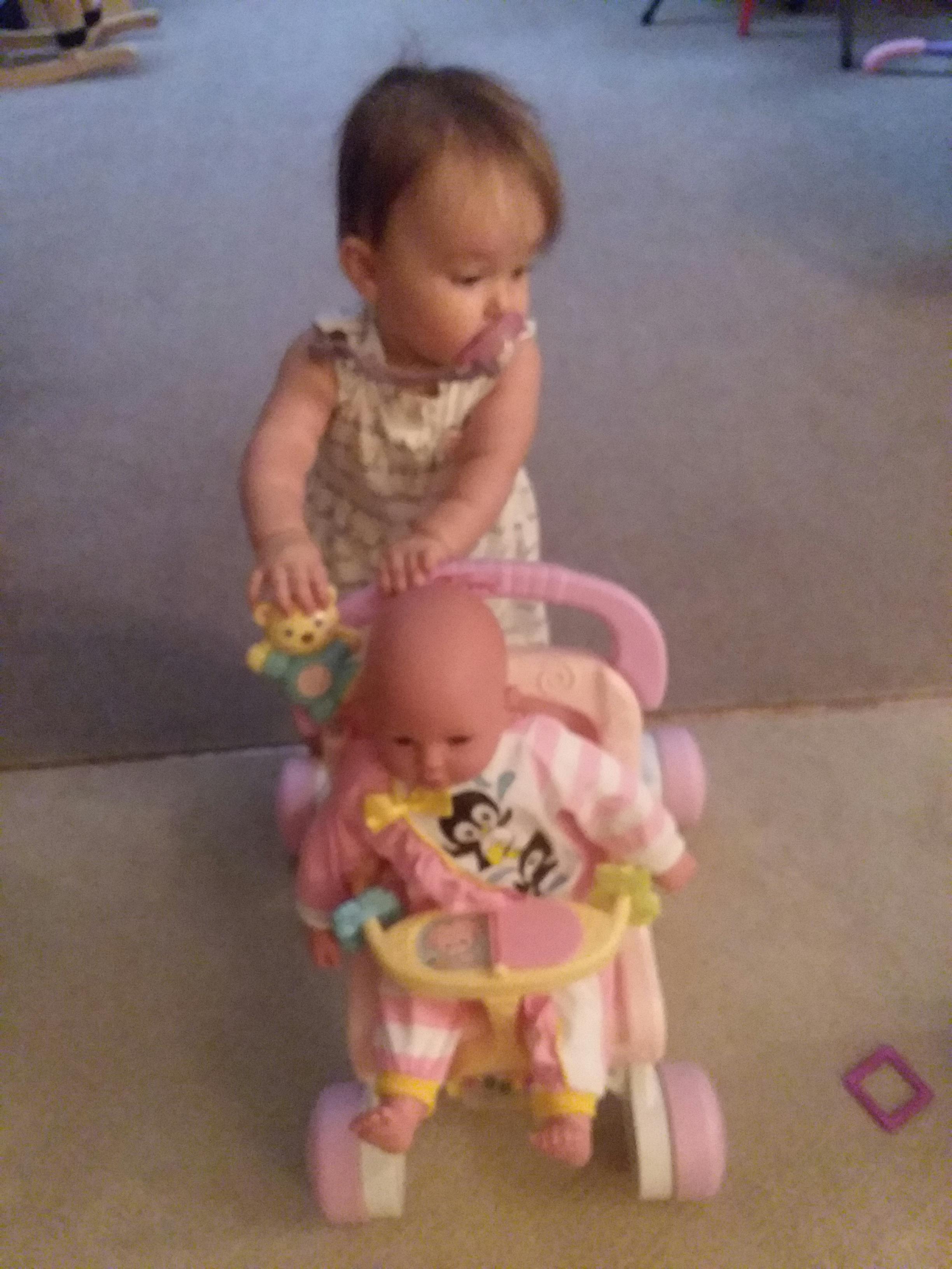 Child pushing a doll in a toy stroller