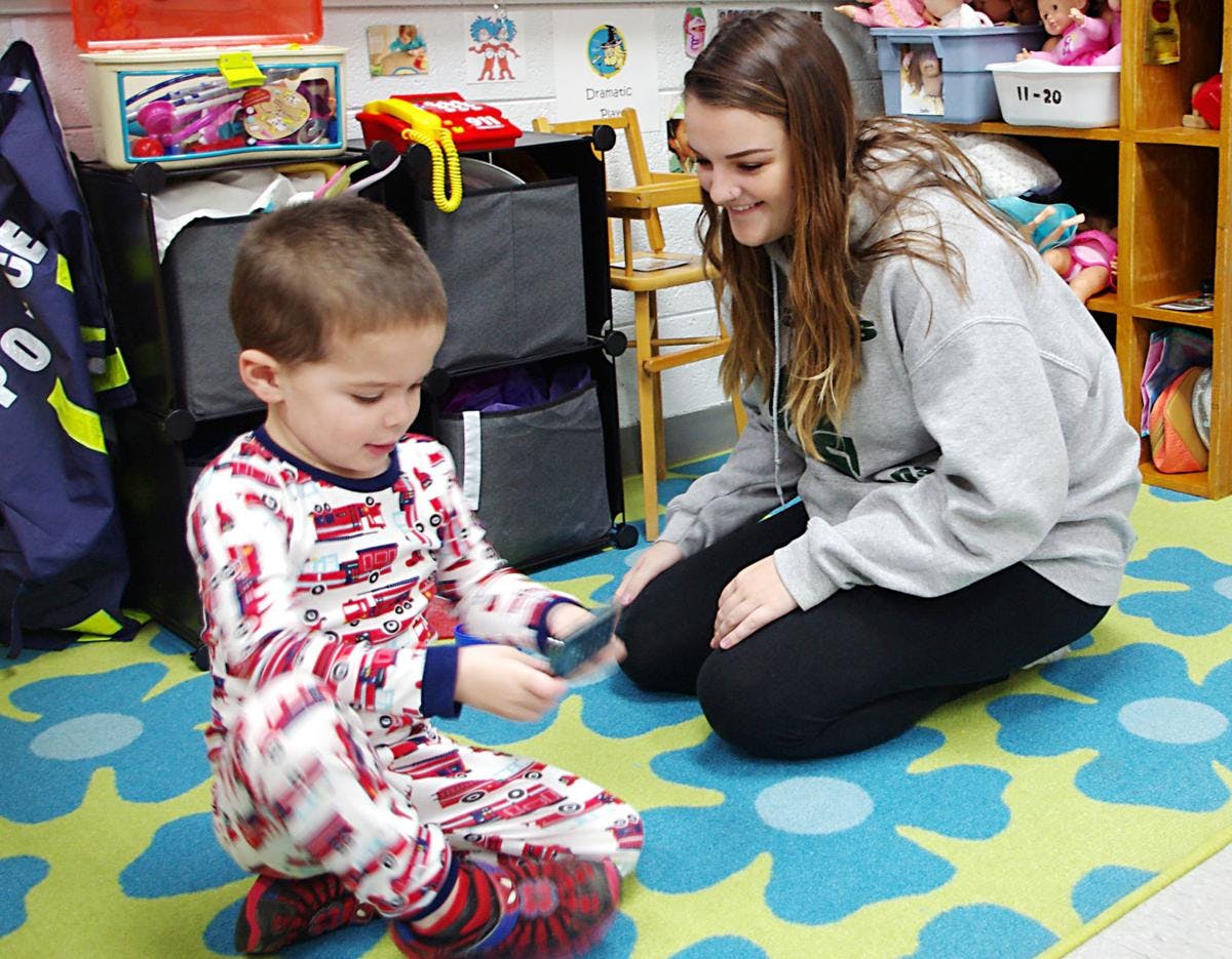Adult and child kneeling on a rug, child holding a small object