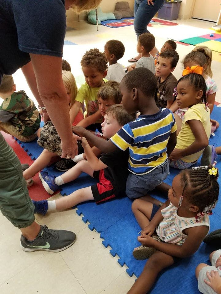 Adult interacting with a group of children sitting on the floor