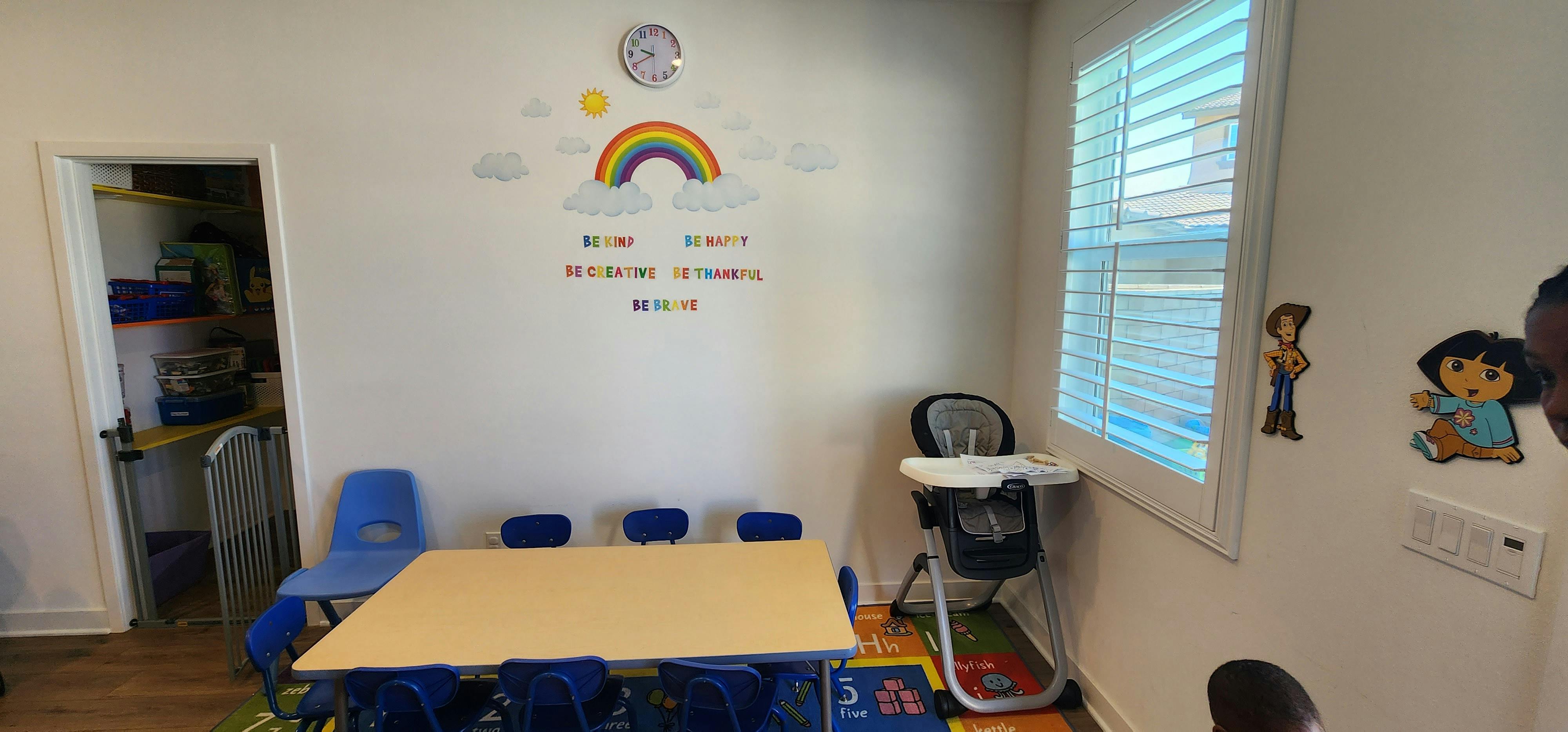 Classroom with small table and chairs, high chair, and rainbow wall decal