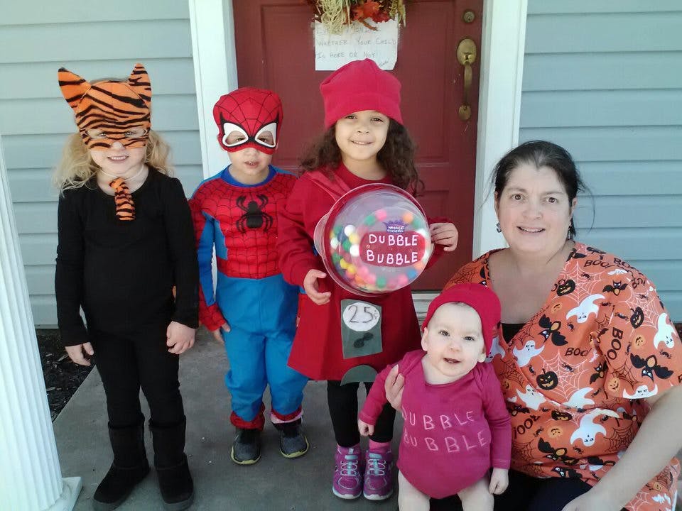 Person with four children in costumes, one holding a bubble gum machine