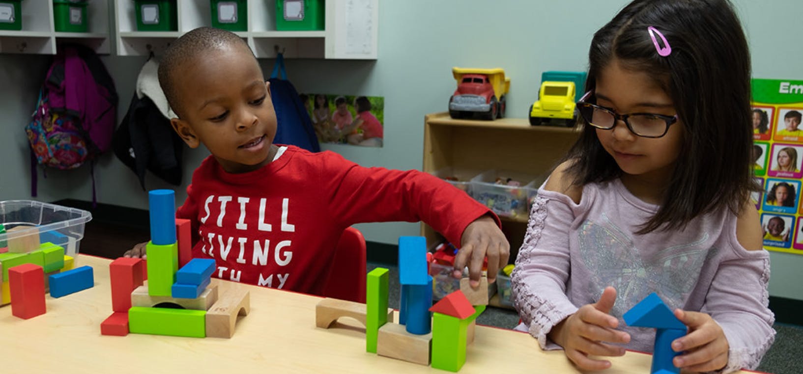 Two children playing with colorful building blocks at a table