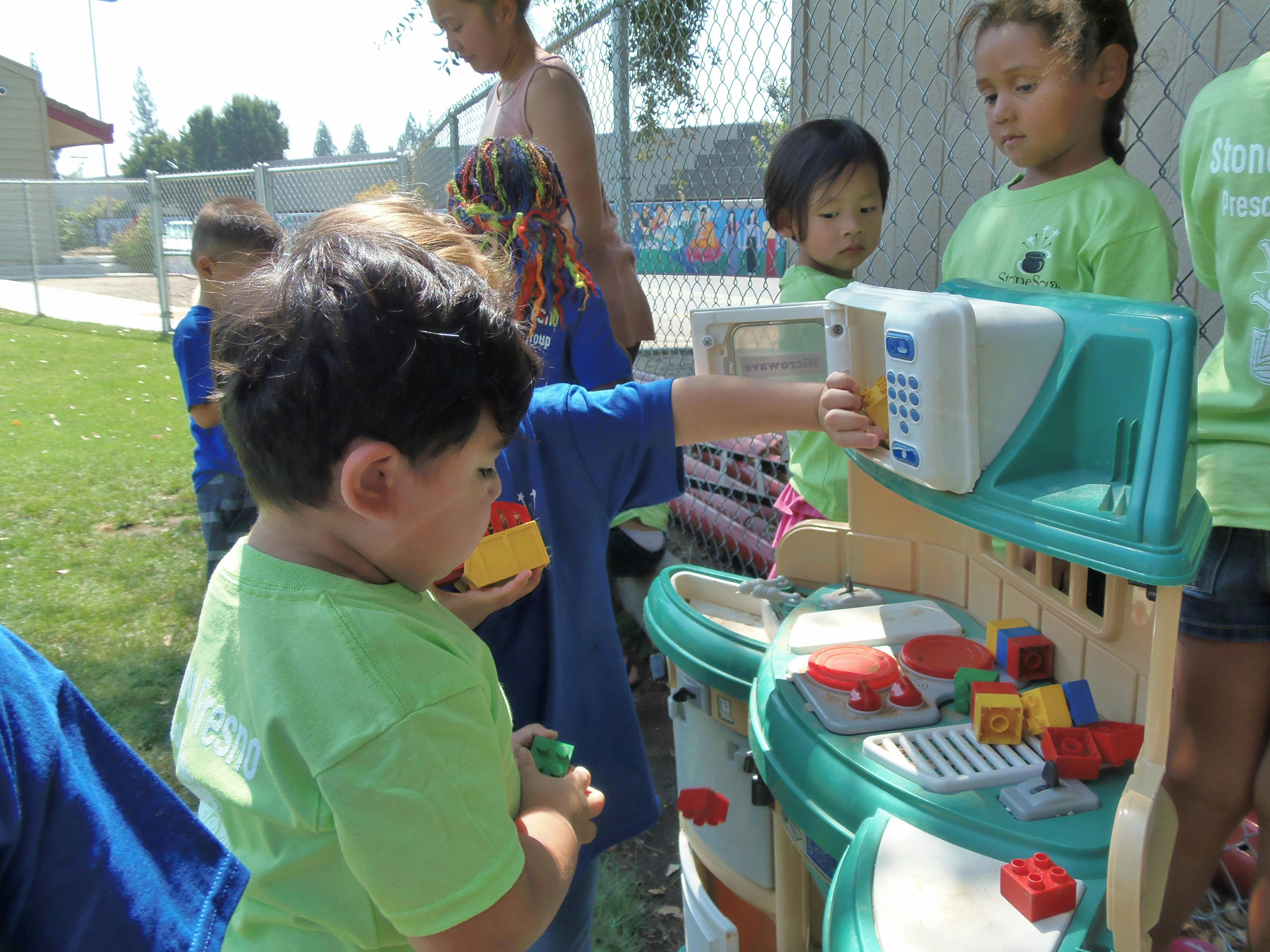 Children playing with a toy kitchen set outdoors