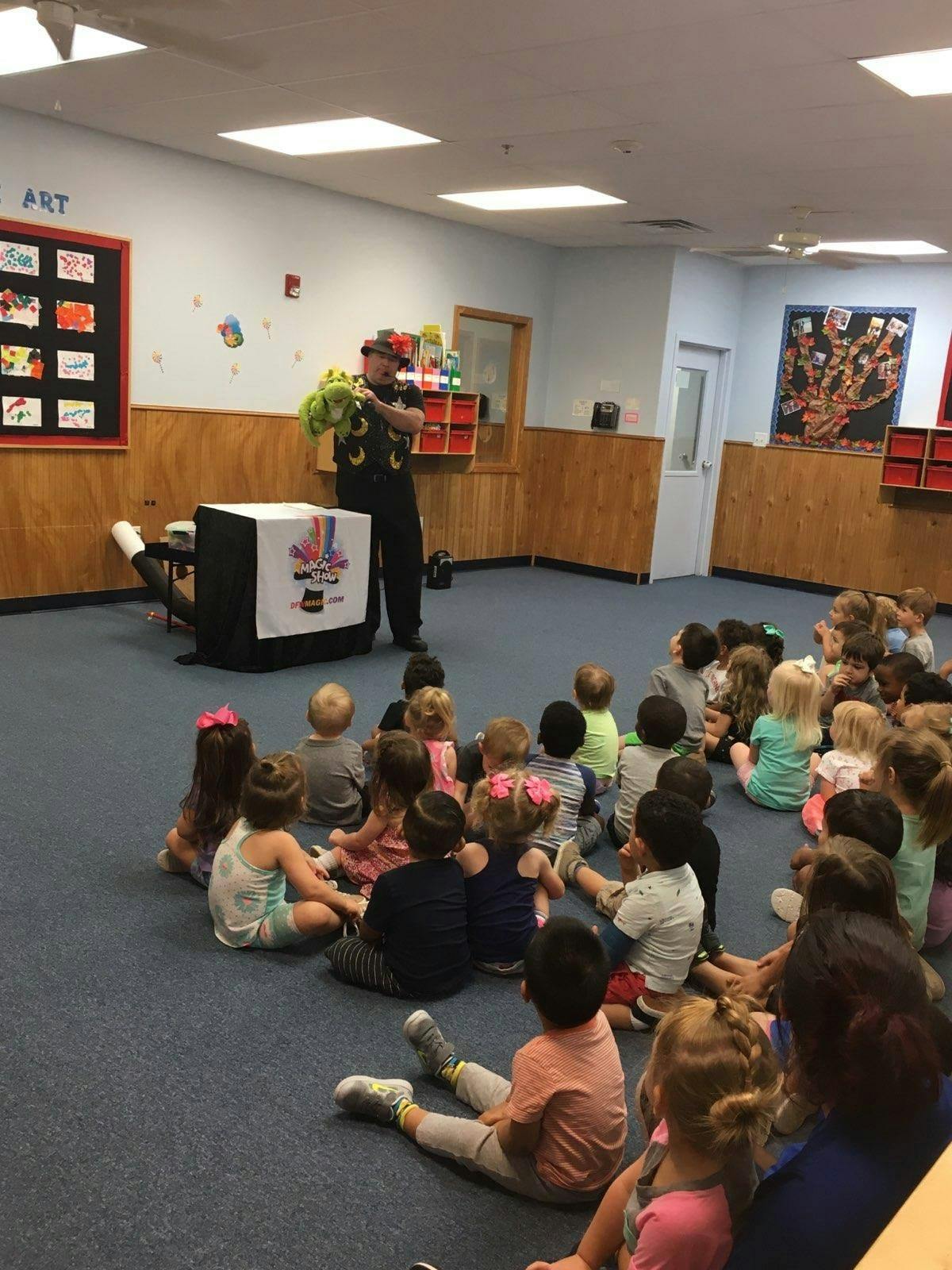 Person holding a puppet for a group of children sitting on the floor