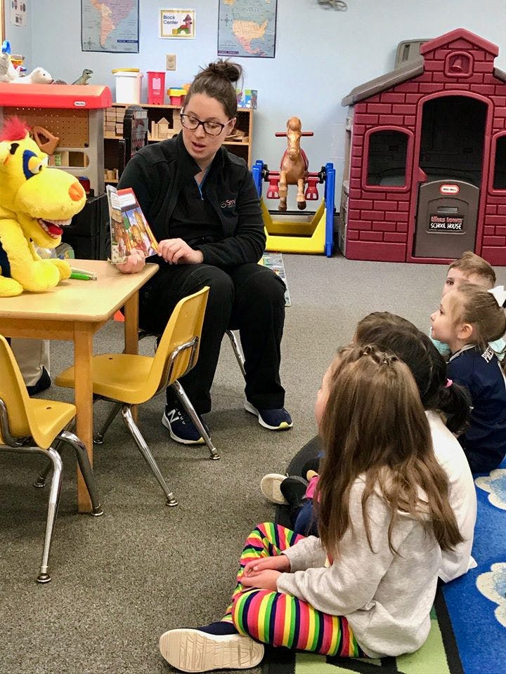 Person reading a book to children in a classroom