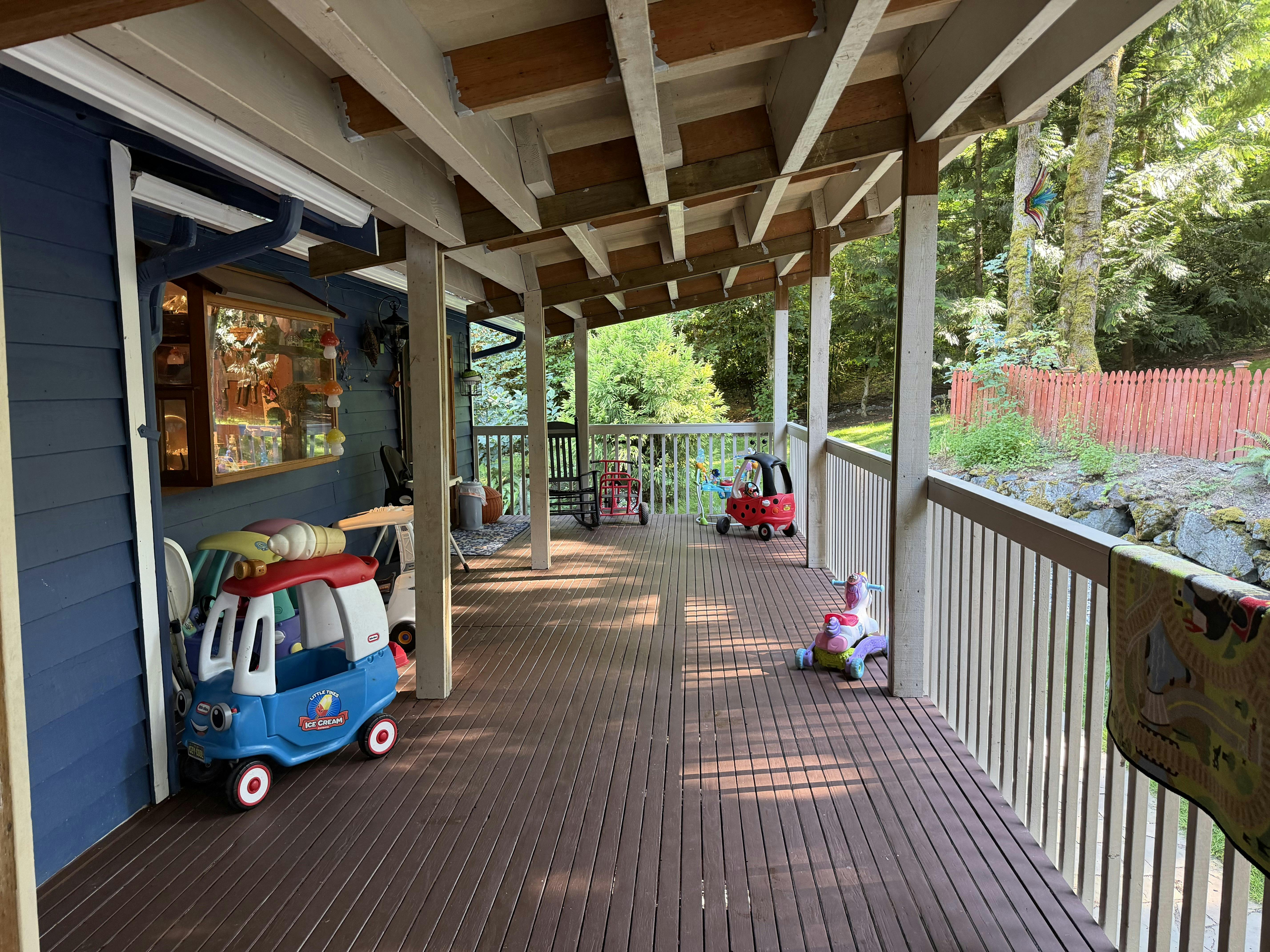Covered wooden deck with toy ride-on cars and child play equipment